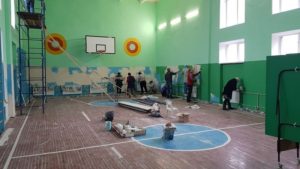 Спортзал загальним планом. Дев’ятеро людей шпаклюють та фарбують стіни.