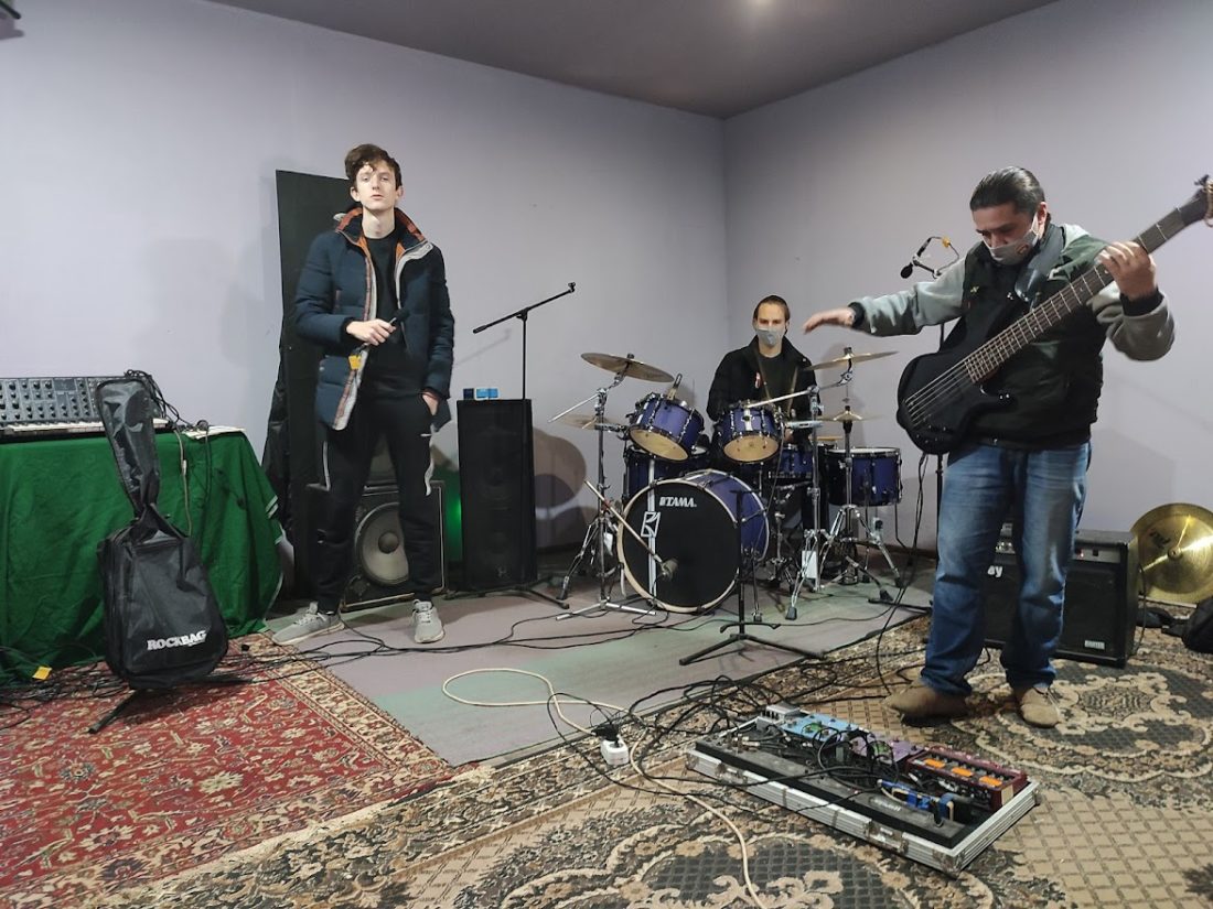 Троє чоловіків у музичній студії в процесі репетиції – соліст, ударник, гітарист