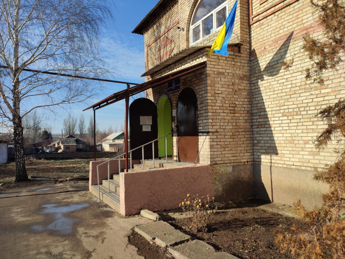 Вхід до цегляної будівлі. Над входом – український прапор