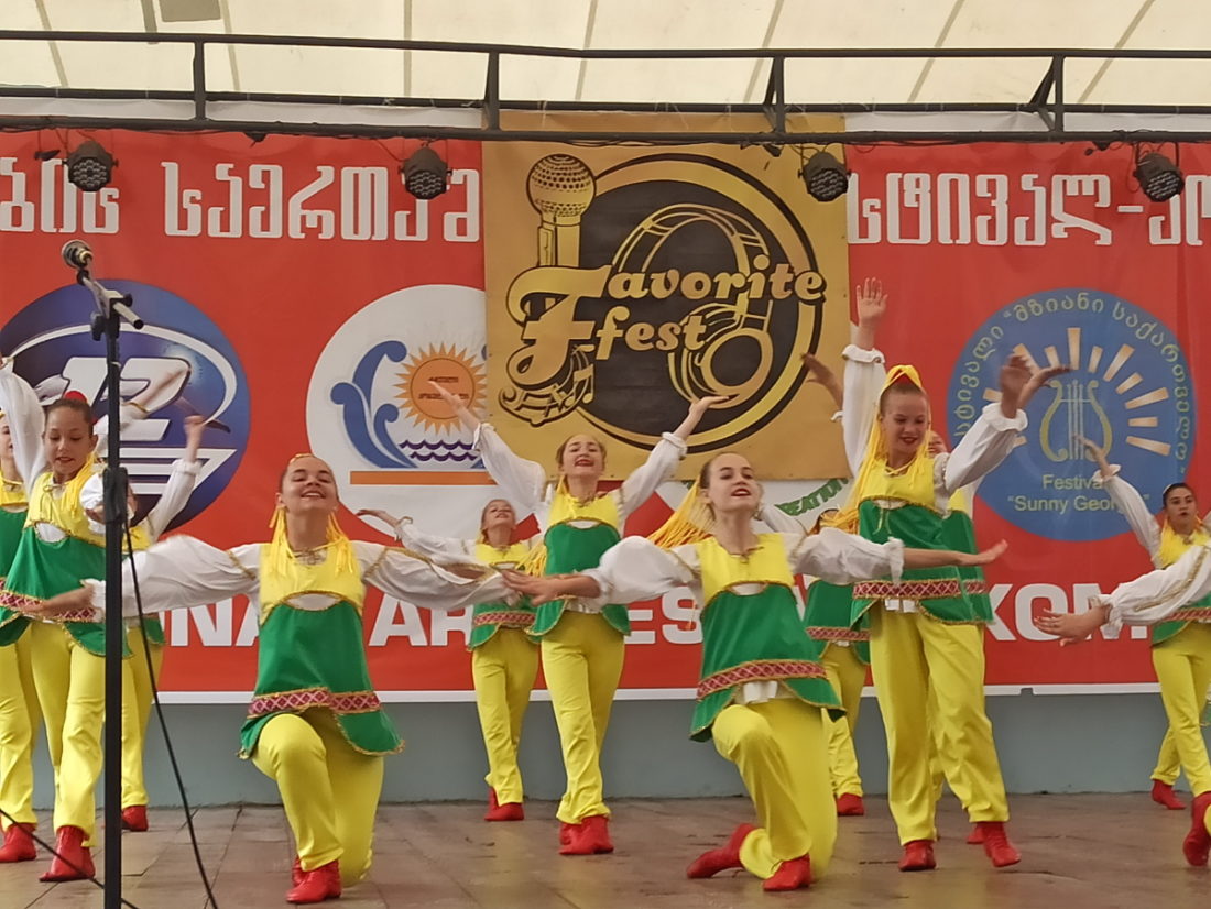Діти танцюють на сцені, на заднику – напис грузинською мовою