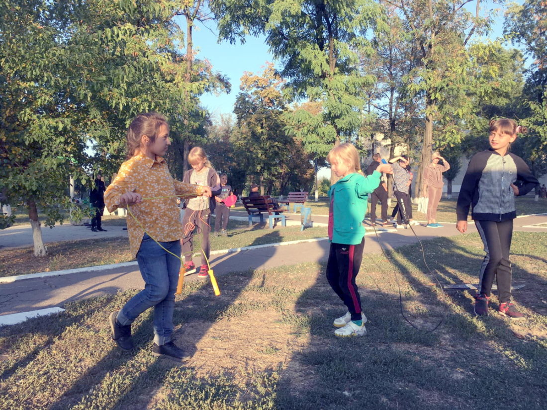 Група дітей бавиться на свіжому повітрі зі скакалками і тенісними ракетками