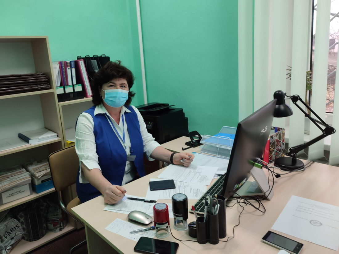Оксана Торопенко в синьому жилеті сидить перед комп’ютером