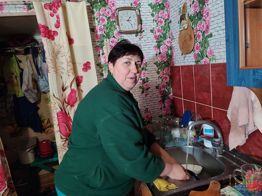 Жінка в кухні миє посуд під краном
