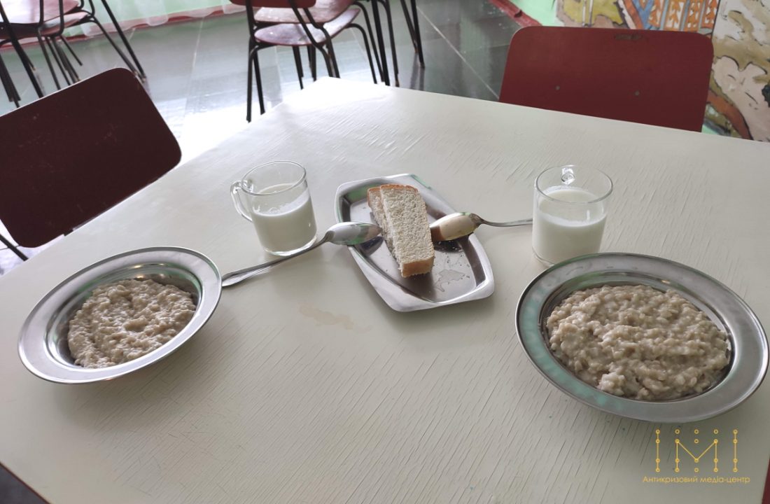 На столі – дві миски з вівсяною кашею, два шматки хліба, дві склянки рідини білого кольору