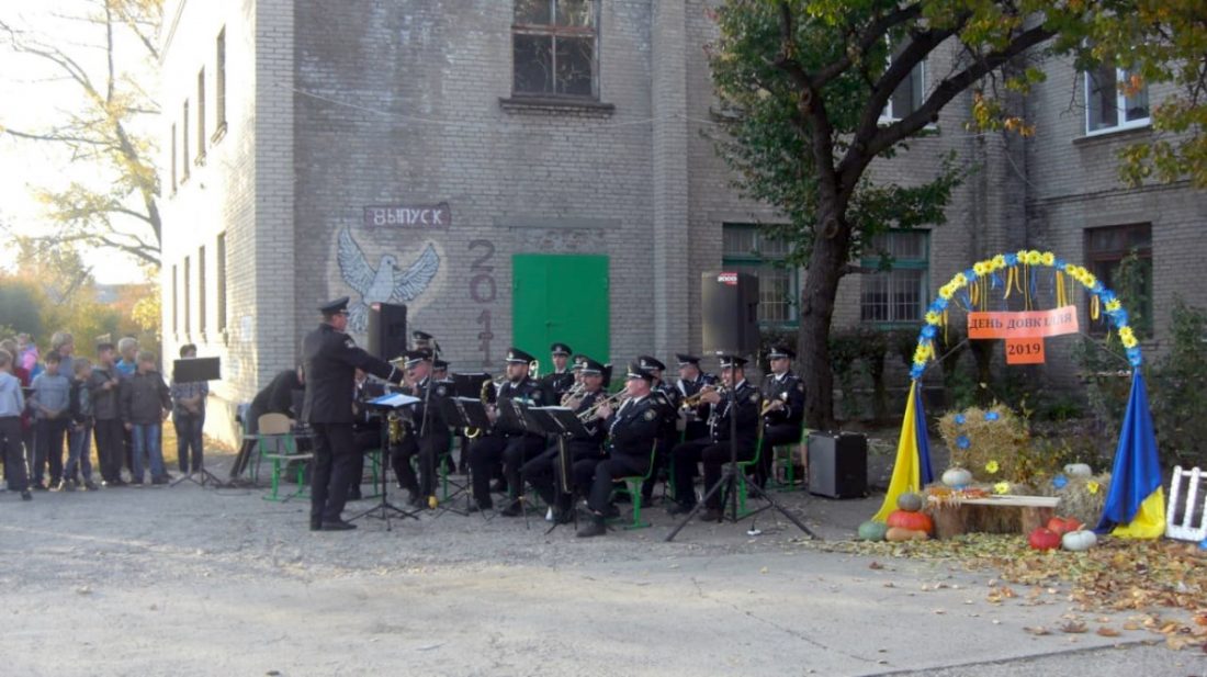 Духовий оркестр в одностроях у дворі школи. Фотозона з написом «День довкілля – 2019»