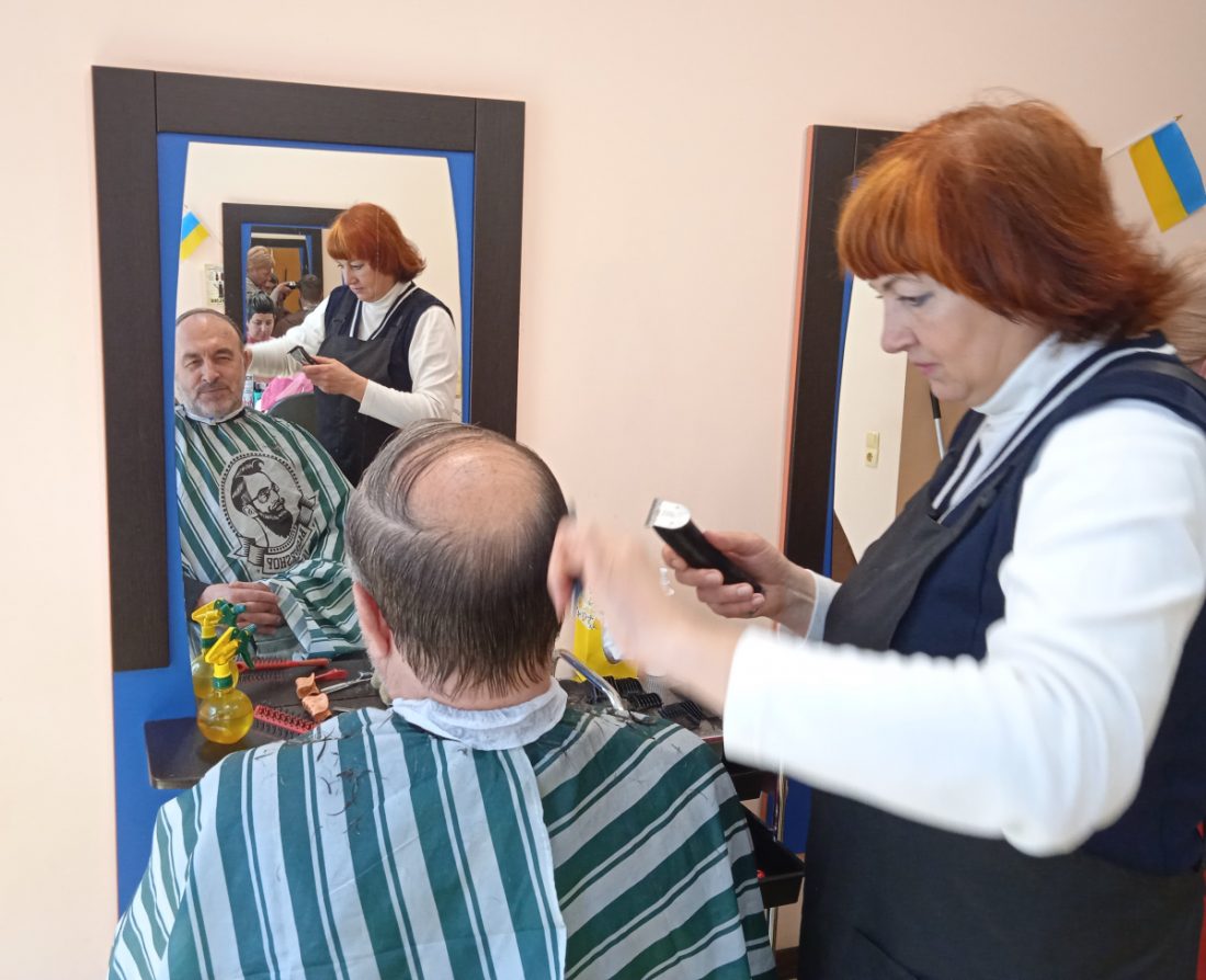 жынка-перукар робить зачіску чоловіку