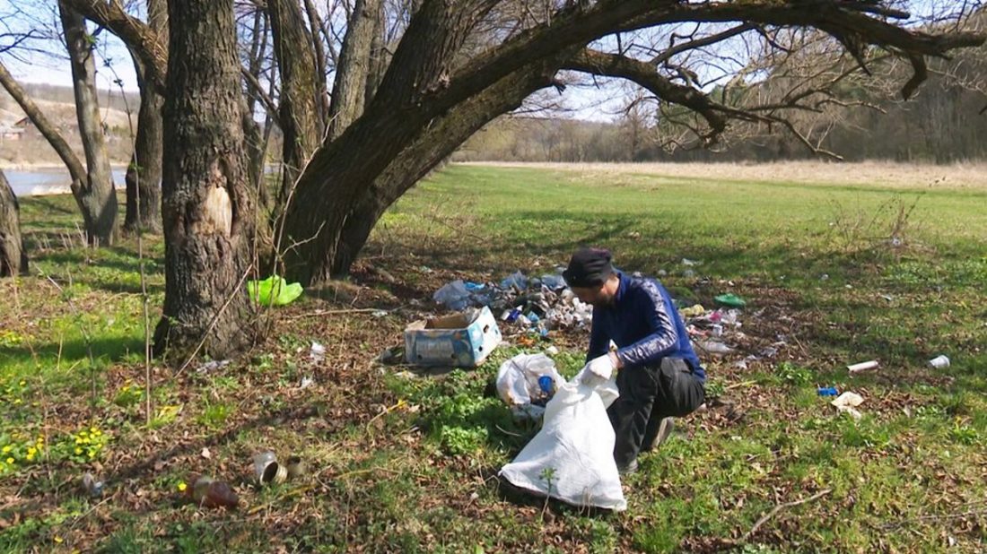 чоловік збирає сміття біля річки